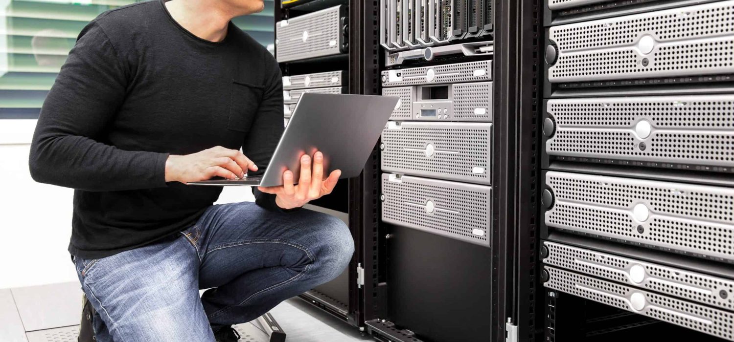 Mid adult IT consultant with laptop monitoring servers in datacenter